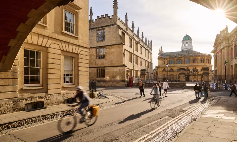 Cyclists passing under Hertford College's Bridge of Sighs in Oxford